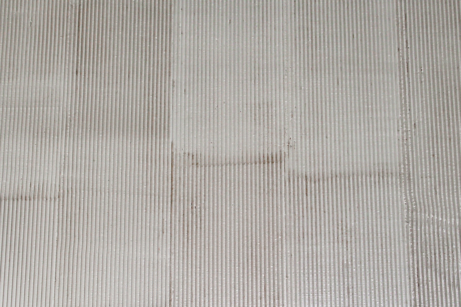 Abstraktní detail rohu žebrované stěrky, geometrické světlo a stín — realizace Dehner